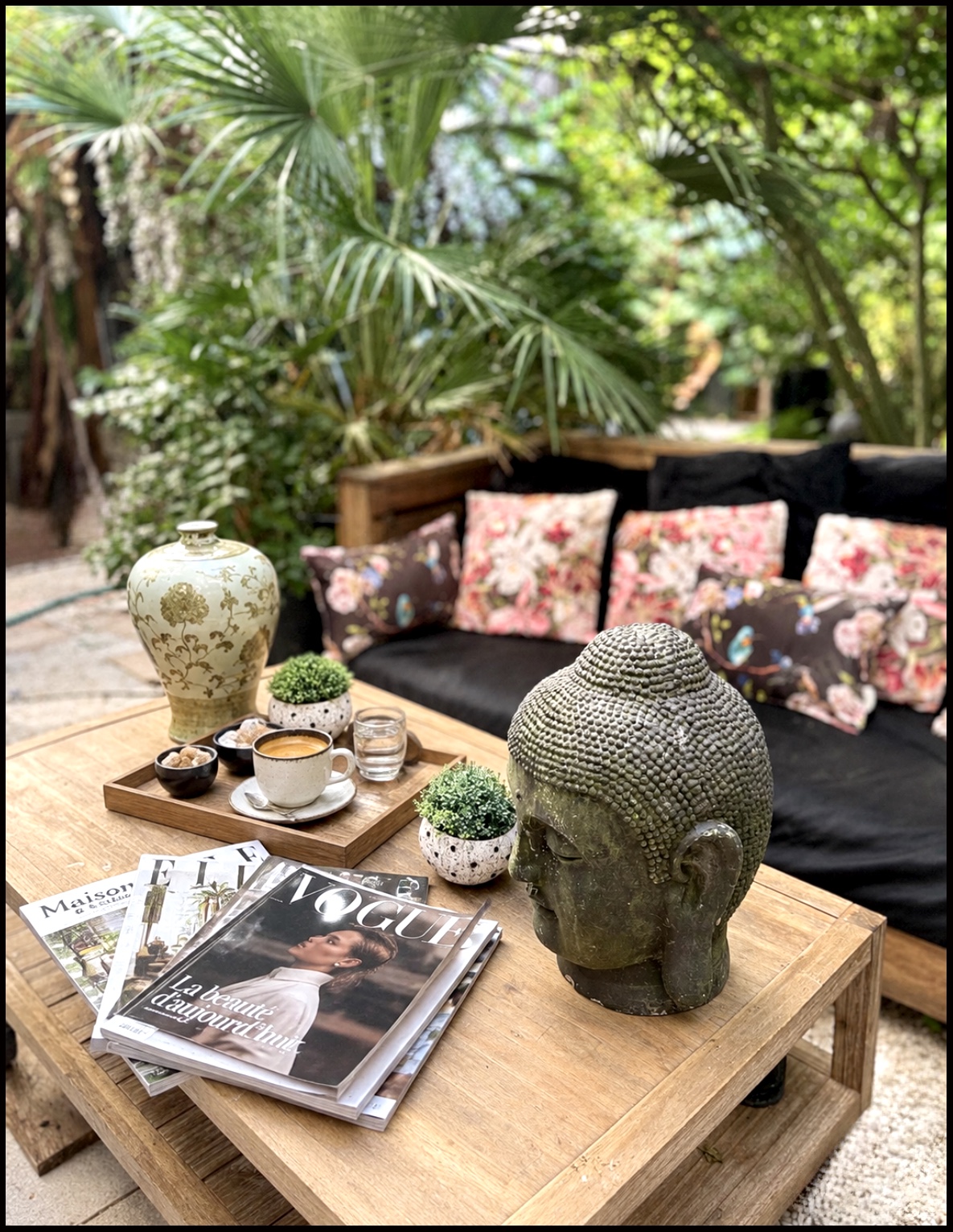 Canapé fleuri et espace détente du jardin avec une tête de Bouddha